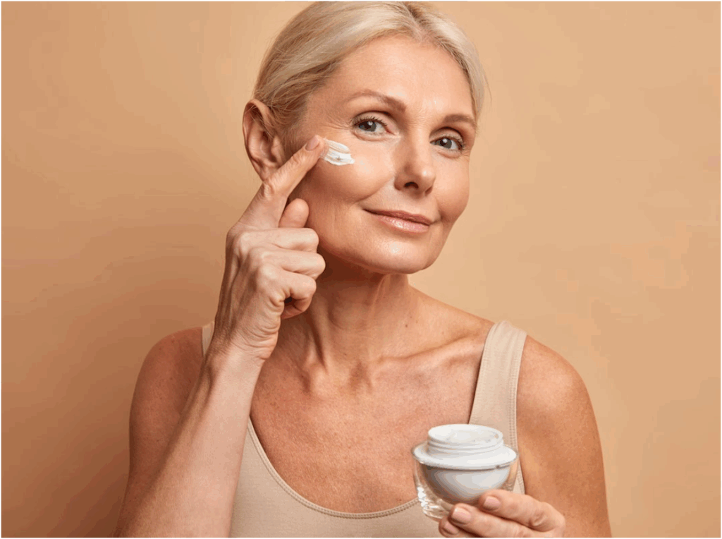 Beautiful older woman applying anti-aging cream on her face to reduce wrinkles
