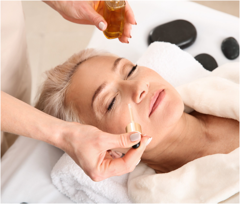 Woman laying down getting a treatment of anti-aging antioxidants drops on her face from a vial