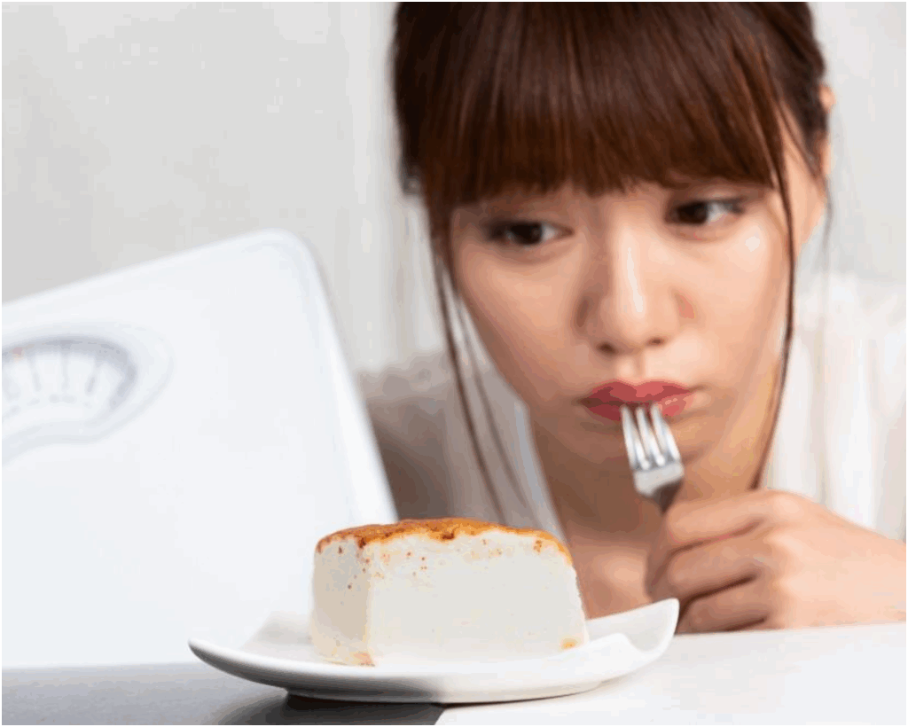 Woman looking at a piece of cheesecake but not hungry