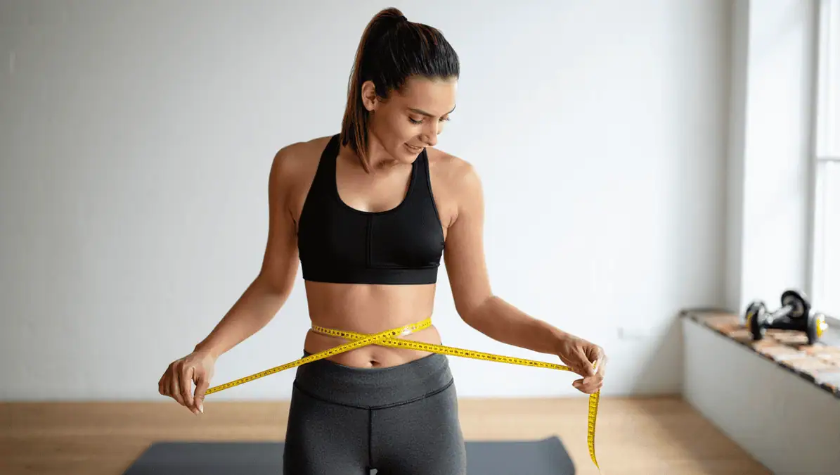 Woman measuring here stomach with a tape measure Woman measuring here stomach with a tape measure