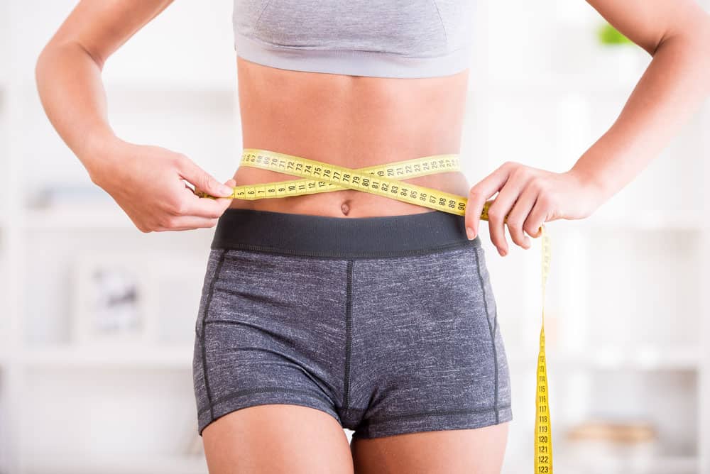 measuring-stomach Woman measuring waist for weight loss progress at a wellness clinic.