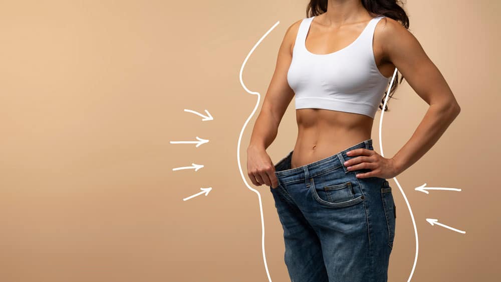 weight-loss Woman measuring waist with loose jeans, weight loss, fitness, healthy lifestyle.