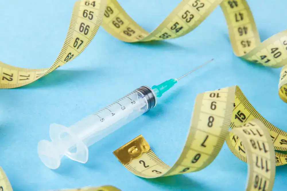 Weight Loss Treatment_Fort Lauderdale (2) Syringe with measuring tape on blue background for weight loss or medical treatment.