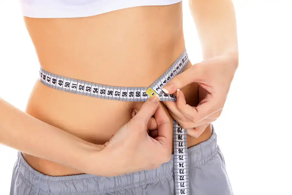 Weight Loss Treatment_Fort Myers Person measuring waist with a tape measure for weight loss progress.