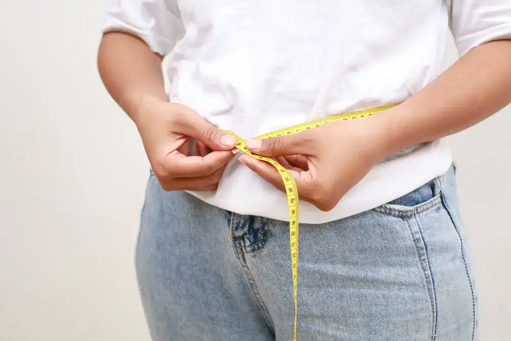 Weight Loss Treatment_Naples (2) Person measuring waist with a yellow tape measure for weight loss progress.