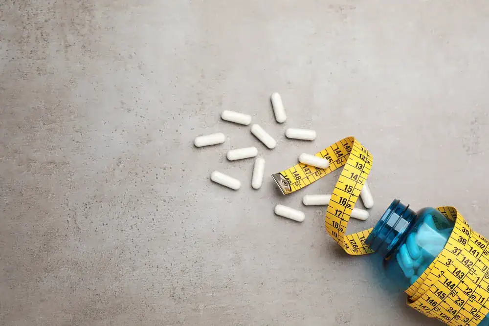 Weight Loss Treatment_Naples Pills and measuring tape for weight loss on a gray background.