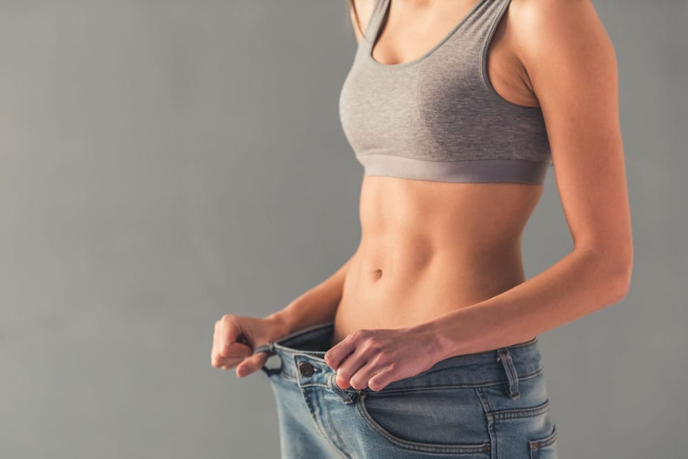 Slim woman measuring her waist for weight loss progress.